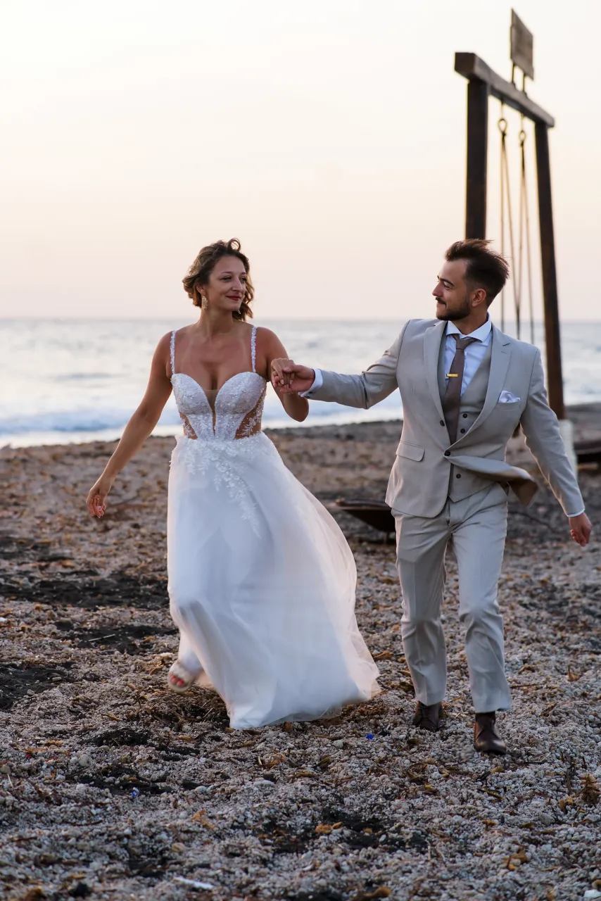 Para biegnąca brzegiem plaży o zachodzie słońca