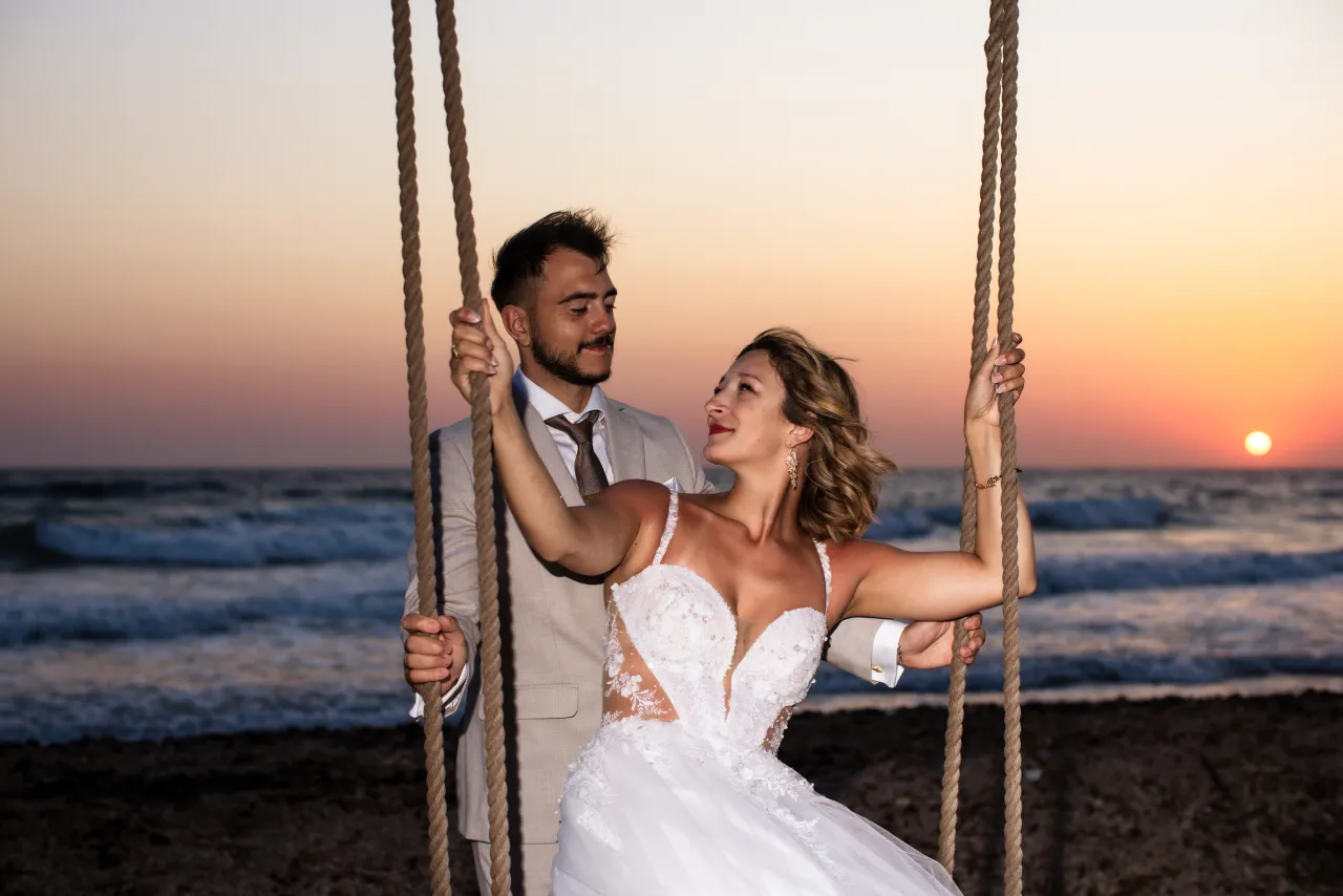 Portret pary przy plażowej huśtawce i zachodzącym słońcu